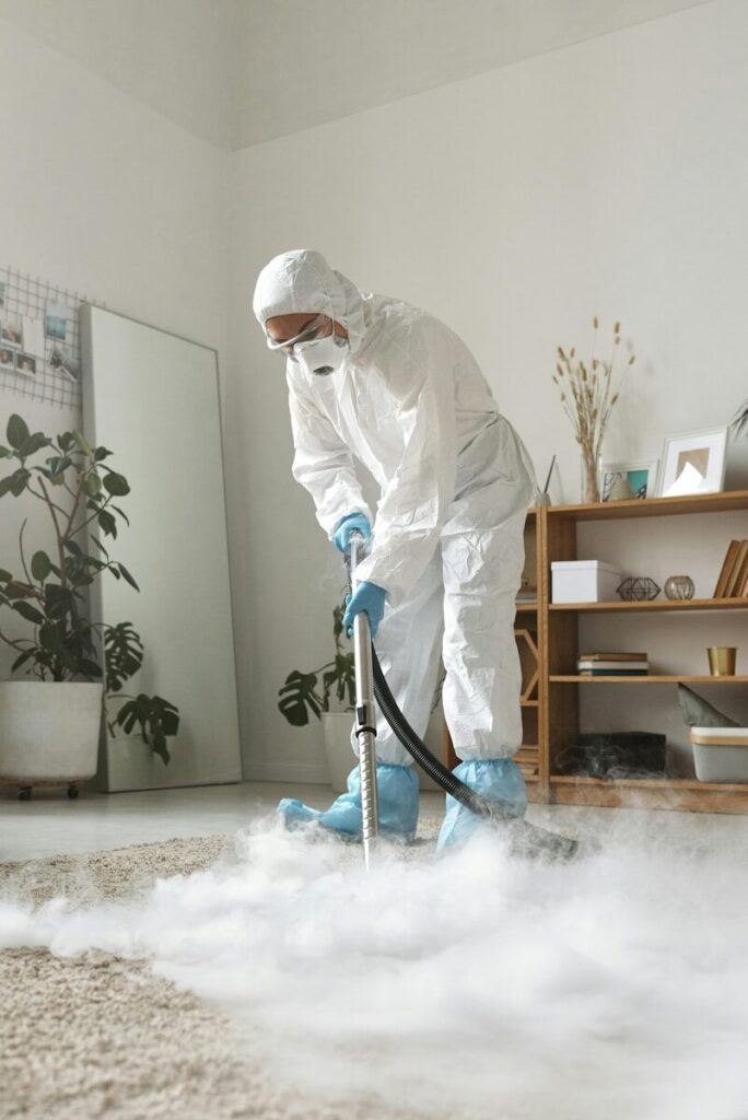 A person in protective suit cleans a carpet.